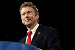 Rand Paul standing behind a podium wearing a suit