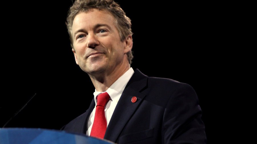 Rand Paul standing behind a podium wearing a suit