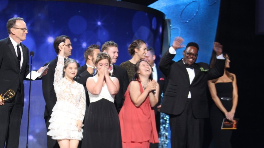 Born This Way cast and producers celebrating their Emmy win on stage at the Emmy Awards. Executive Producer Jonathan Murray holds the Emmy Award.