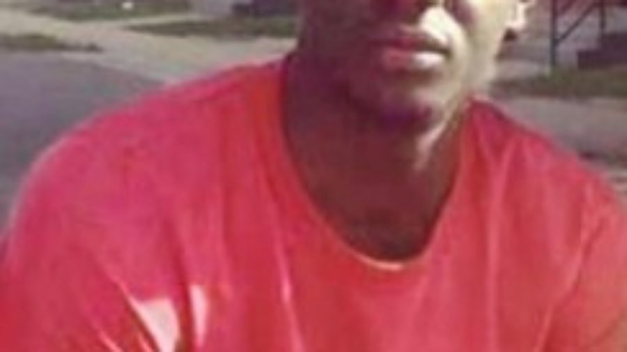 Headshot of Freddie Gray in a red t-shirt outside in front of homes