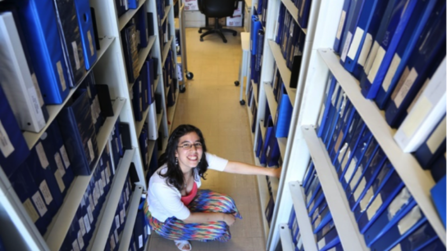 Young woman kneeling in a library organizing files