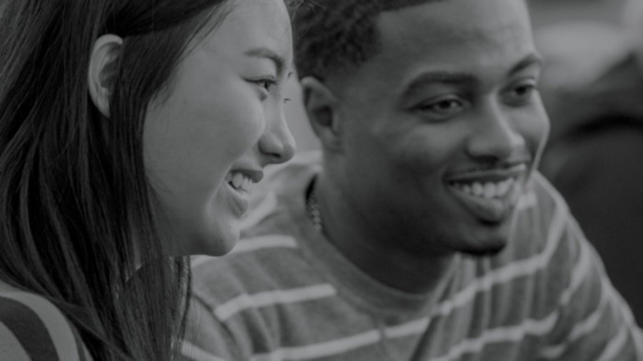 Image of two young adults at a computer smiling