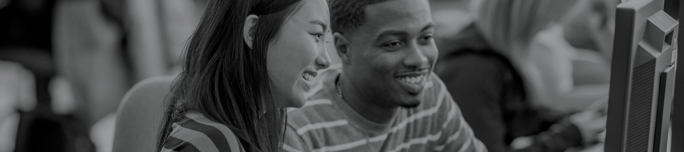 Image of two people smiling and looking at a computer.