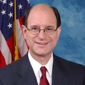 headshot of Brad Sherman wearing a suit in front of an American flag