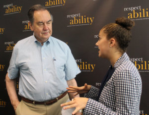 Cal Thomas talking with RespectAbility Fellow Brilynn Rakes in front of RespectAbility banner