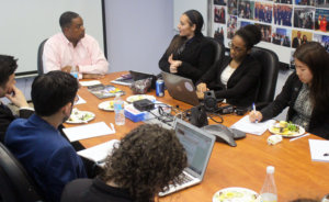 Gerard Robinson seated at head of brown table with Fellows seated around the other sides listening to him