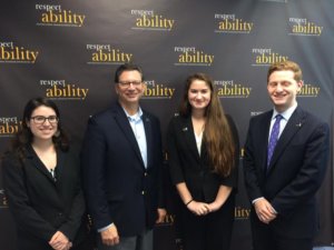 Four individuals standing in front of a RespectAbility banner smiling for the camera