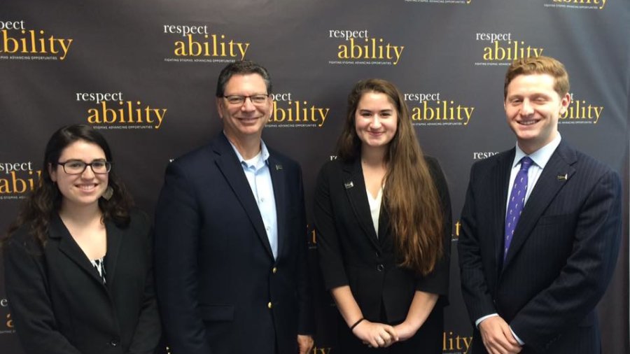 Four individuals standing in front of a RespectAbility banner smiling for the camera