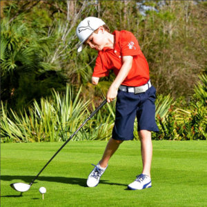 Tommy Morrissey, who has just one arm, golfing wearing blue shorts and a red collared shirt and baseball cap