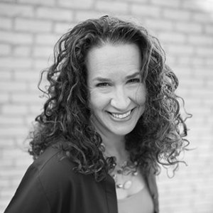 headshot of Dana Marlowe smiling at the camera she has long curly hair grayscale photo