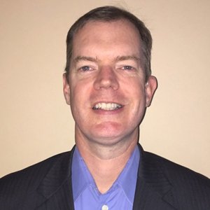 headshot of Delbert Whetter smiling and facing the camera wearing a blue button down shirt color photo