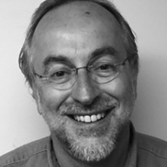 headshot of Doc Sweitzer smiling wearing glasses and a collared shirt, with a light beard and mustache grayscale photo