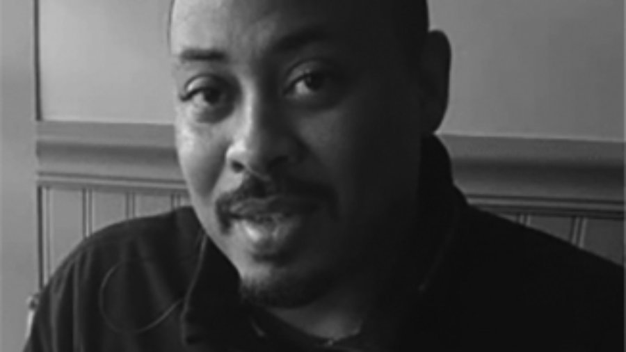 headshot of Eddie Ellis he is bald and he has a mustache grayscale photo