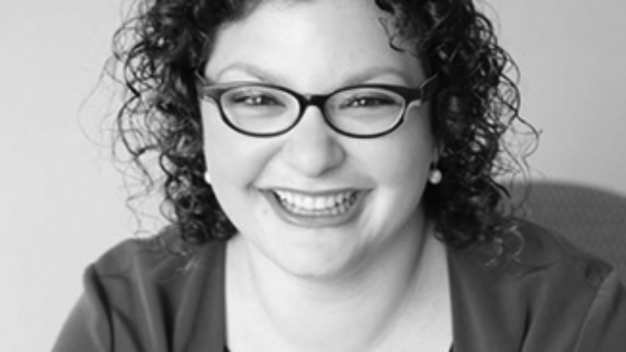 headshot of Emma Adelman smiling with curly hair grayscale photo