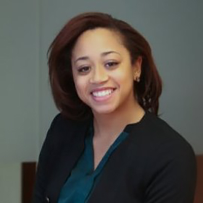 Evelyn Kelley is smiling and she has her hair loose, she is wearing a black blouse and small earrings color photo