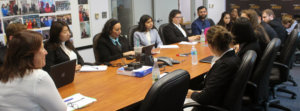 Fran Katz Watson sitting at table with Fellows around her listening to her speak