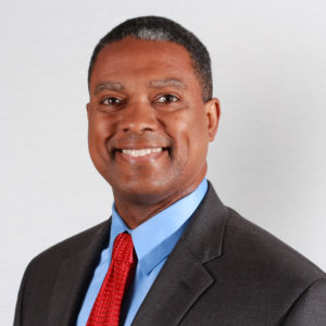 headshot of Gerard Robinson smiling and facing the camera wearing a black suit blue shirt and red tie color photo