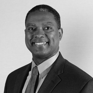 headshot of Gerard Robinson smiling and facing the camera and wearing a suit and tie grayscale photo