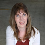 Heidi Daroff facing the camera and wearing a white cardigan and red shirt color photo