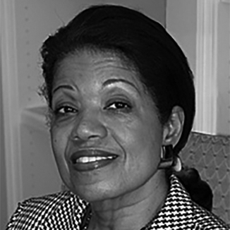 headshot of Janie L. Jeffers smiling and wearing lipstick, earrings, and a patterned jacket grayscale photo
