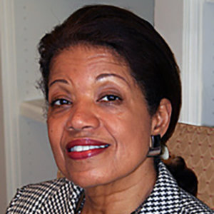 headshot of Janie L. Jeffers smiling and wearing red lipstick, earrings, and a black and white patterned jacket color photo