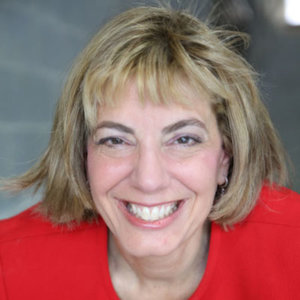 Headshot of Jennifer Mizrahi, smiling and facing the camera wearing a red blazer color photo