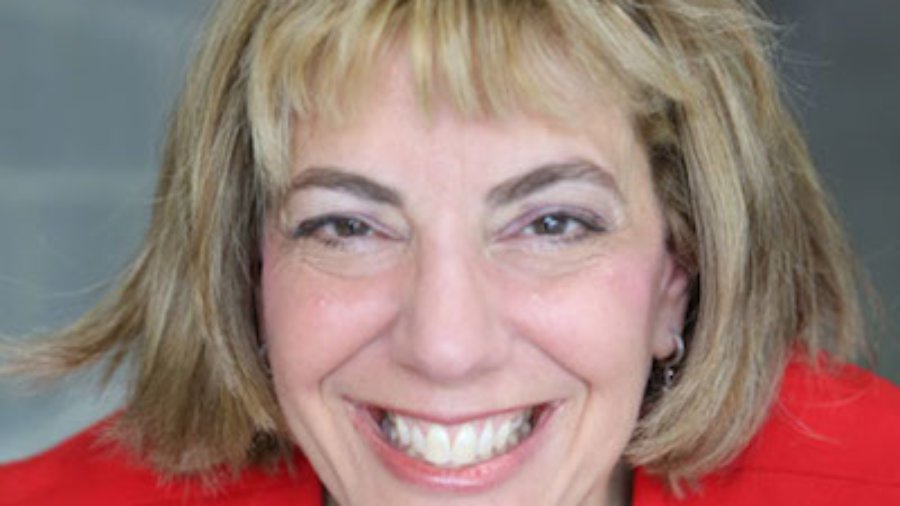 Headshot of Jennifer Mizrahi, smiling and facing the camera wearing a red blazer color photo