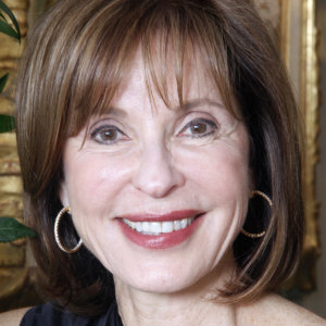 headshot of Judith Creed with medium length hair and wearing hoop earrings smiling and facing the camera color photo