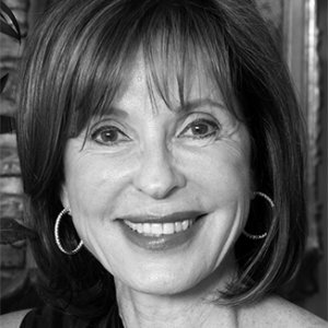 headshot of Judith Creed with medium length hair and wearing hoop earrings smiling and facing the camera grayscale photo