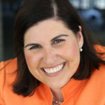 head shot of Lauren wearing an orange blazer, smiling and facing the camera color photo