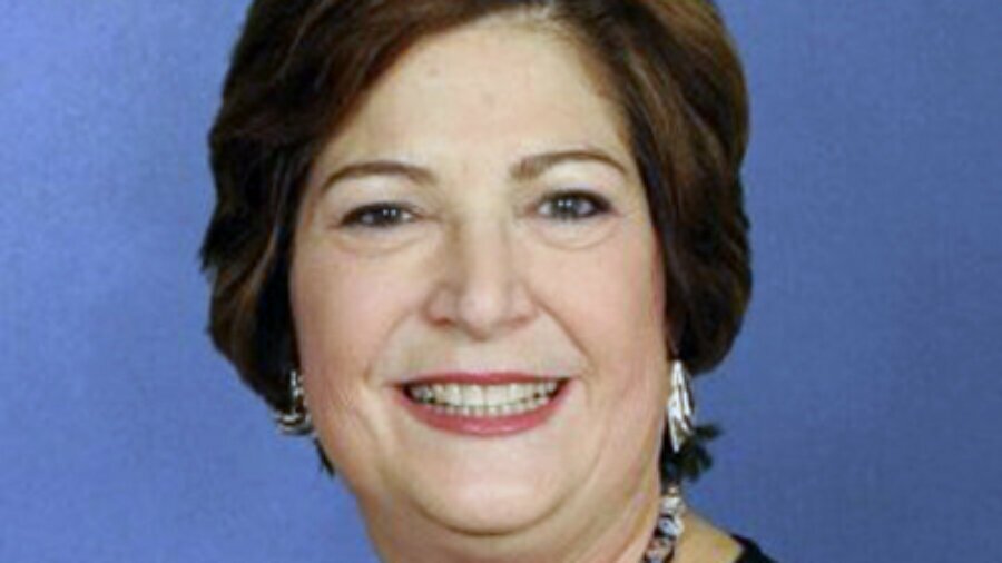 headshot of Linda Burger, who is smiling and wearing dangly earrings and a chunky necklace and a stripy shirt color photo