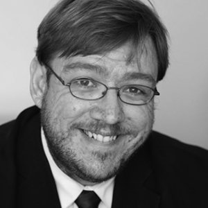 headshot of Philip Kahn Pauli wearing glasses with beard and mustache grayscale photo