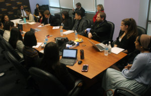 Fellows listening to Pras Ranaweera talking while seated around a long brown conference table