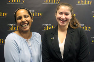 Image of Pras and Rachael laughing while standing in front of a RespectAbility banner