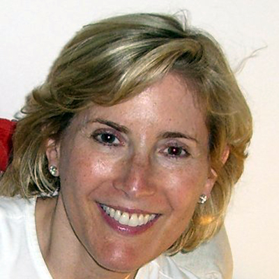 Shelley Cohen is smiling at the camera, her blonde hair is messy and she is wearing small earrings grayscale photo