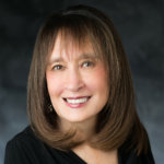 headshot of Vivian Bass smiling at the camera with long hair color photo