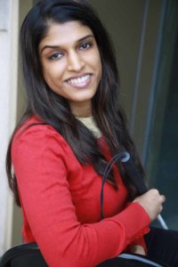 Headshot of Khadija Bari smiling leaning against a wall