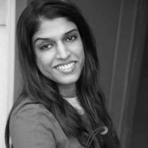 Headshot of Khadija Bari smiling leaning against a wall