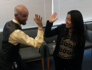 Murray and Policy Fellow, Ana Song doing funny poses and reaching their hands together like they are about to do a high five. Ana is and Murray are smiling. 