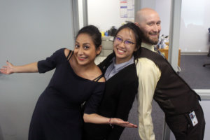 Marisela is on the left smiling and doing a cute pose. Judith is in th middle with a big smile and also leaning to the right. Murray is on the right and has his back to the girls but is leaning backward in a silly pose. 