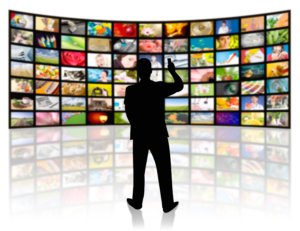 back view of a young man watching a big tv panel