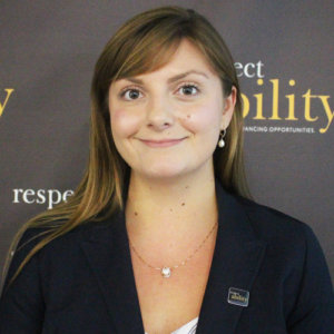 RespectAbility Fellow Julia Wood smiling in front of the RespectAbility banner