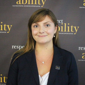 RespectAbility Fellow Julia Wood smiling in front of the RespectAbility banner