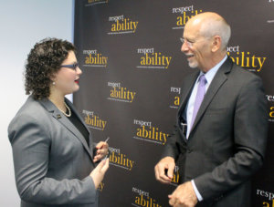 RespectAbility Fellow Emma Adelman and Patrick McCarthy talking in front of a RespectAbility banner