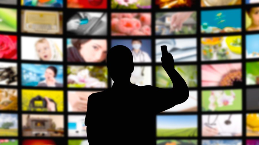 back view of a young man watching a big tv panel