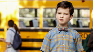 Nine-year-old Sheldon wearing a bow tie in front of a school bus
