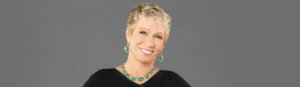 Barbara Corcoran standing with her hands at her hips posing for the camera wearing a black top and jade jewelry