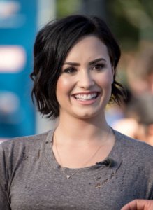 Demi Lovato smiling wearing a brown top