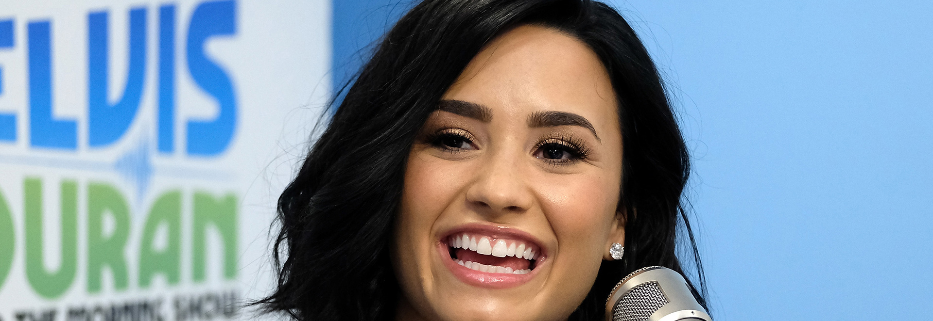 Demi Lovato smiling at a microphone