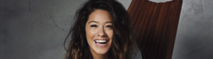 Gina Rodriguez smiling, seated on a chair